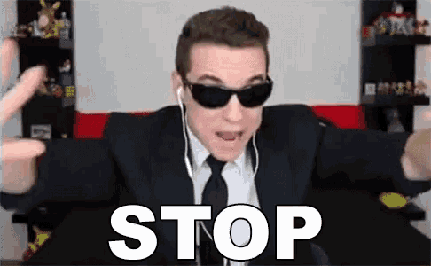 a man in a suit and tie is wearing sunglasses and ear buds and says stop