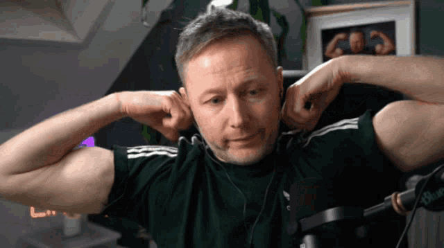 a man wearing headphones and a green shirt is covering his ears