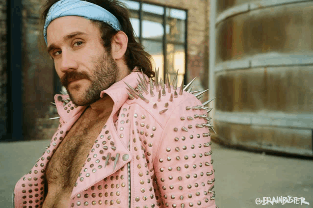 a man with a beard wearing a pink jacket with spikes on it