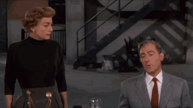 a man in a suit and tie stands next to a woman