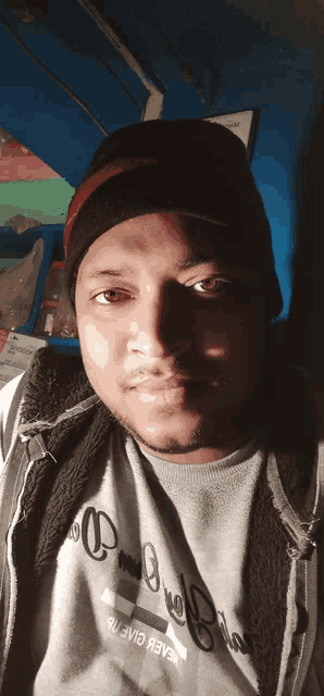 a man wearing a beanie and a grey shirt that says " believe "