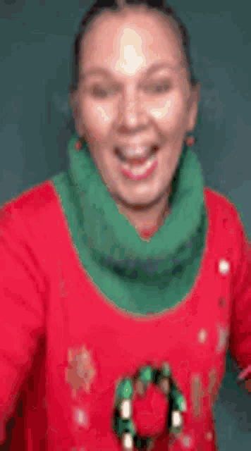 a woman is wearing a red sweater and a green scarf .