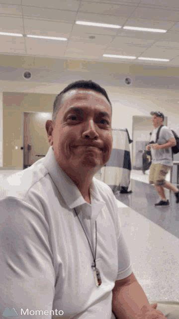 a man in a white shirt is smiling in a momento app