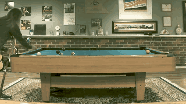 a pool table in a room with a poster on the wall that says ' a few dollars '