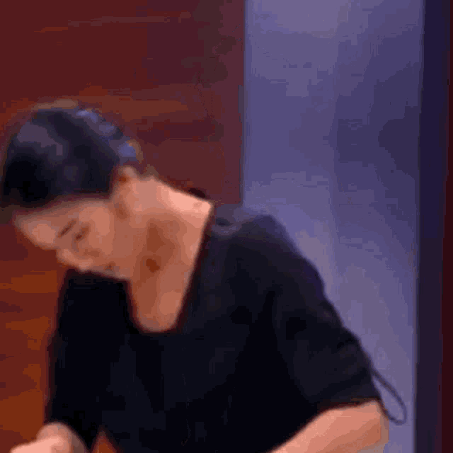 a woman in a black shirt is standing in front of a wall .