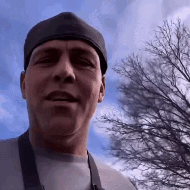 a man wearing a black hat and an apron looks at the camera