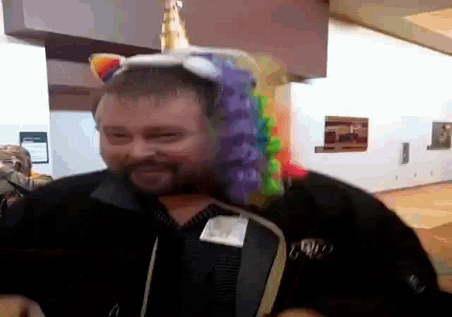 a man with a beard wearing a unicorn hat with a rainbow tail
