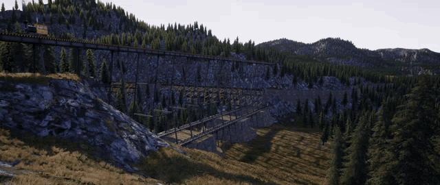 a train is going over a bridge in the mountains with trees on the side