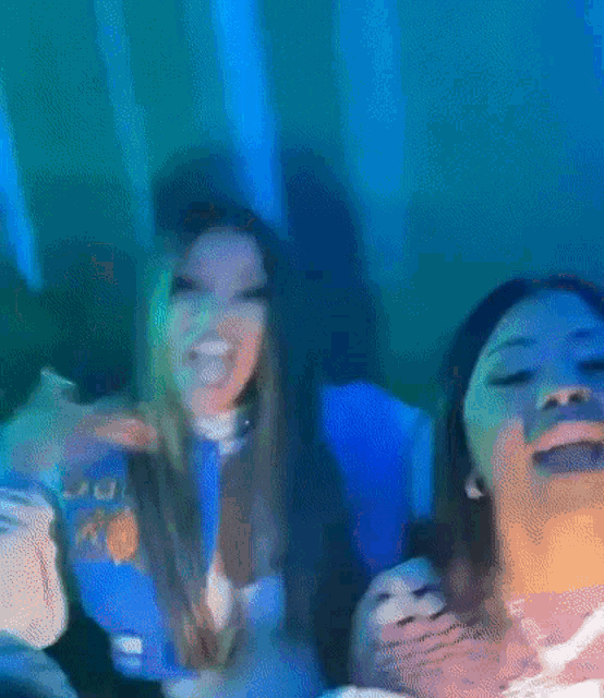 a couple of women are sitting next to each other in a room with blue lights .