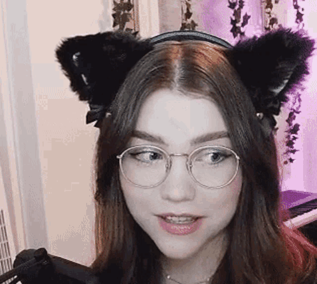 a woman wearing glasses and a headband with cat ears is looking at the camera .