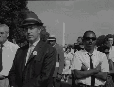 a man in a suit has a button on his jacket that says ' i am a proud american '