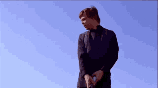 a man in a black shirt is tied to a rope with a blue sky in the background