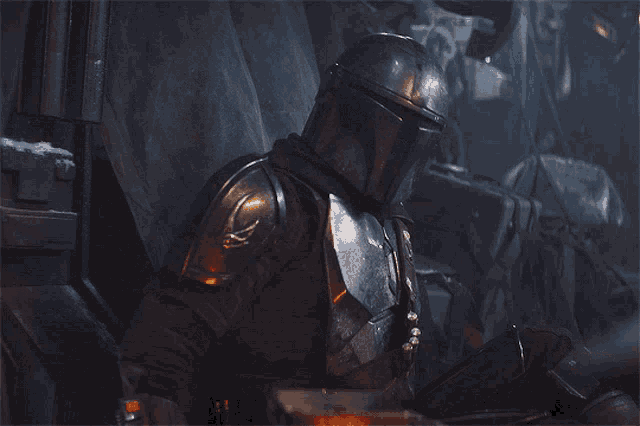 a man in a helmet is sitting in a dark room looking down