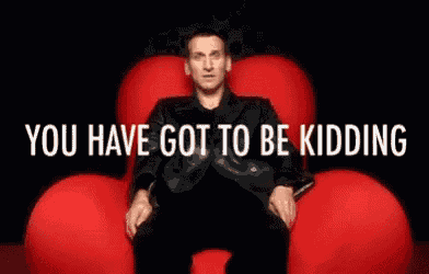 a man in a suit is sitting in a red chair with the words you have got to be kidding behind him