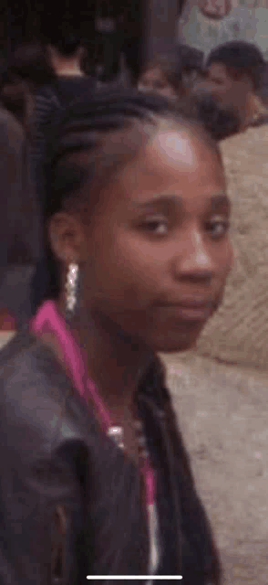 a close up of a woman 's face with braids in her hair and earrings .