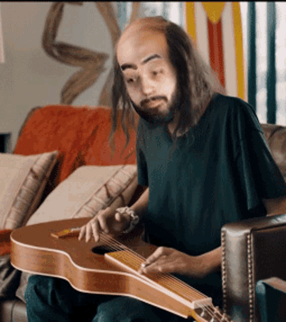 a man with a beard is playing a guitar in a living room