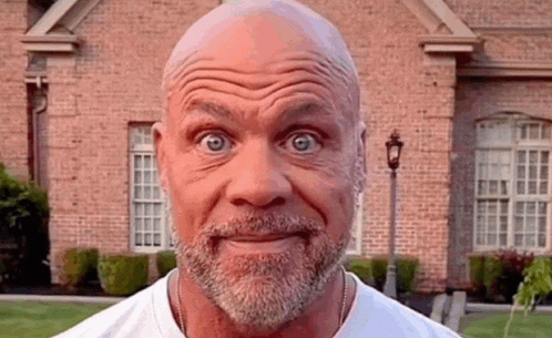 a man with a beard is making a funny face in front of a brick house .