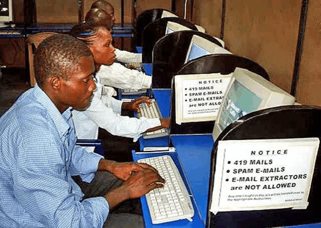 a man is typing on a computer in front of a sign that says notice 419 mails spam e-mails