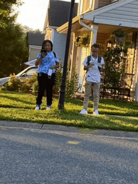 a man and a woman are standing in front of a house looking at a map