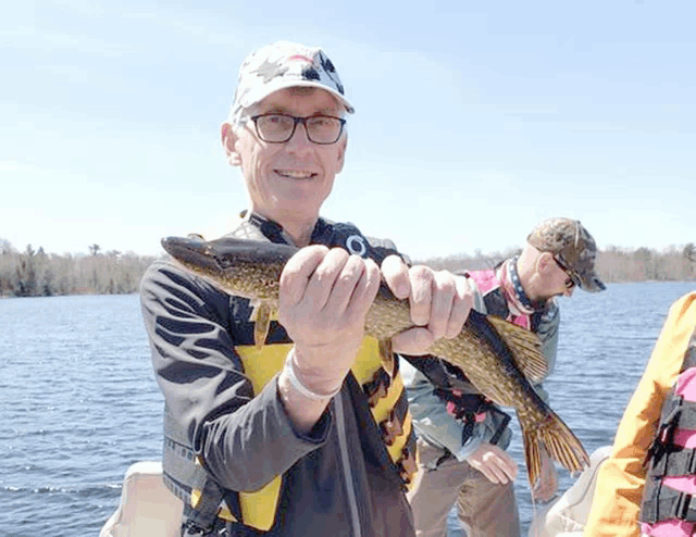 a man on a boat holds a fish in his hands