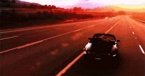 a car is driving down a highway with a sunset behind it