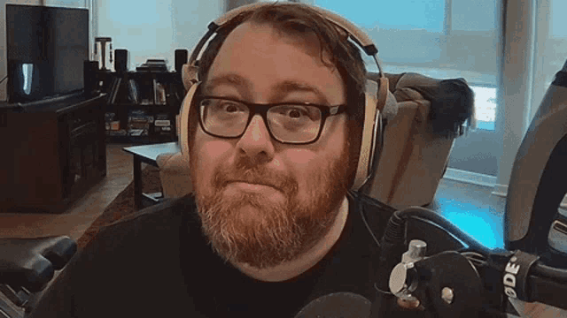 a man with a beard and glasses wearing headphones and a microphone with the word rode on it