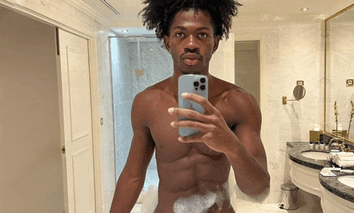 a shirtless man is taking a selfie in a bathroom