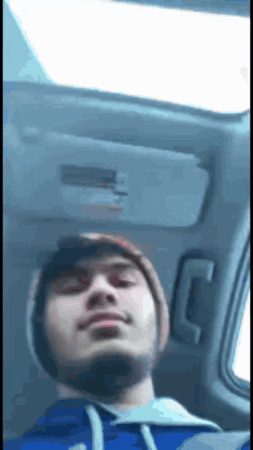 a man in a blue hoodie is sitting in the back seat of a car