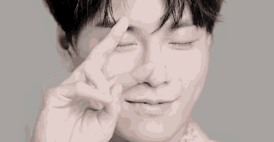 a close up of a young man making a peace sign with his fingers .