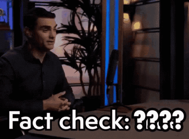 a man sitting in front of a microphone with the words " fact check " written on the screen