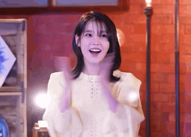 a woman in a yellow sweater is clapping her hands