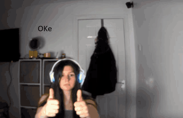 a woman wearing headphones is giving a thumbs up with the word oke behind her