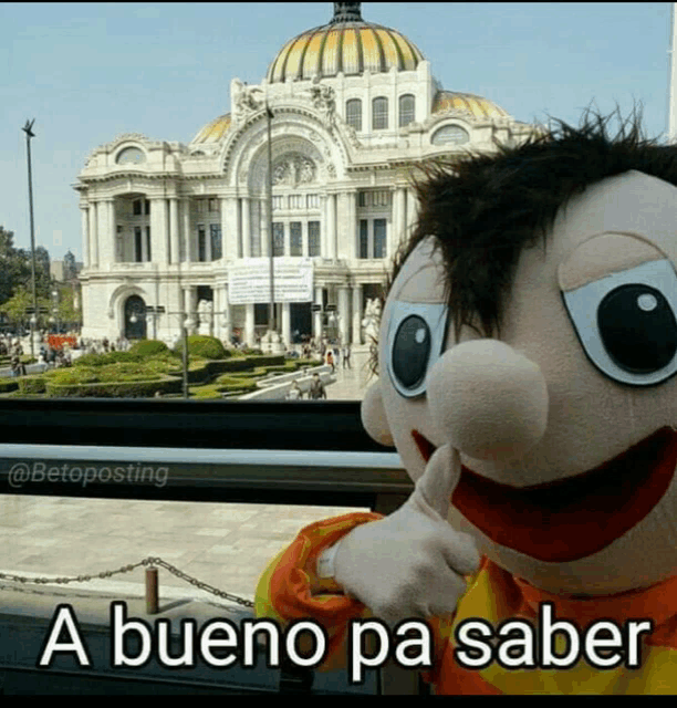 a stuffed animal giving a thumbs up in front of a building that says " a bueno pa saber "