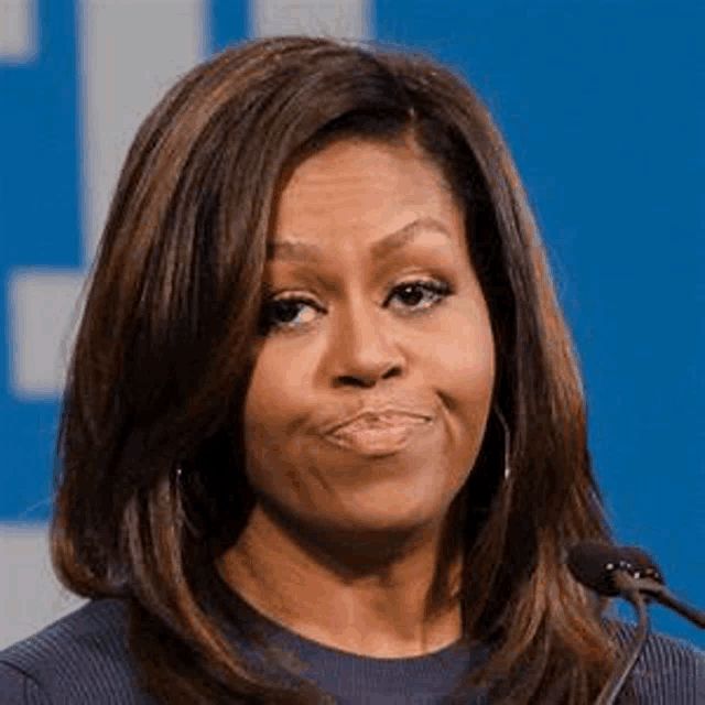 michelle obama is smiling and talking into a microphone .