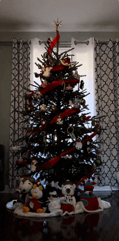 a black christmas tree with red ribbons and decorations