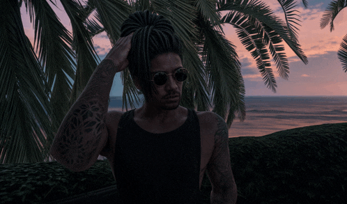 a man with dreadlocks wearing sunglasses and a black tank top