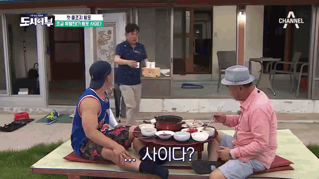 a group of men are sitting around a table with a sign that says channel a above them