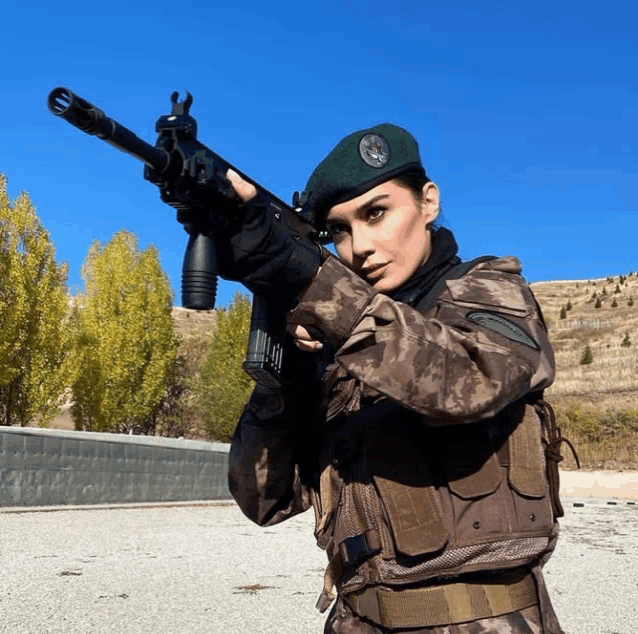 a woman in a military uniform holds a rifle