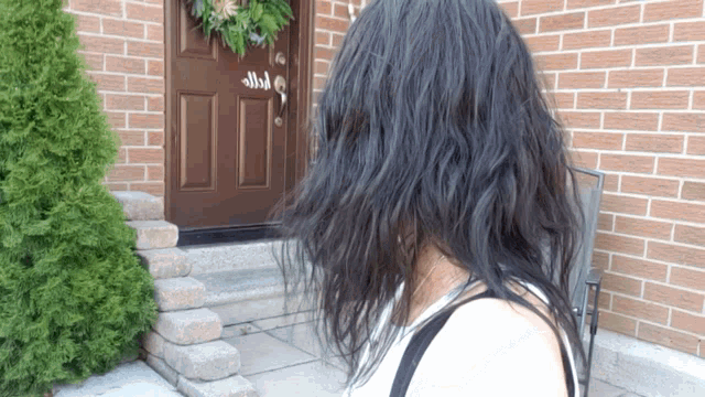 a woman stands in front of a brick building with a brown door that says ' n ' on it