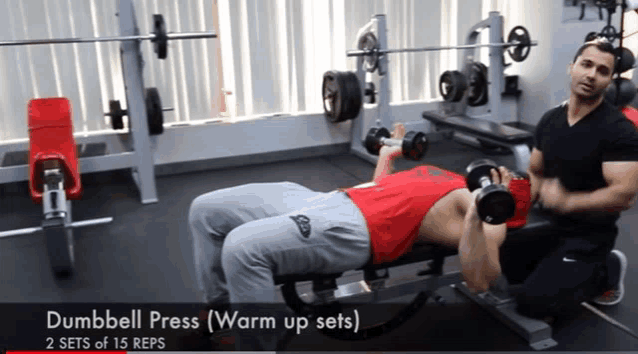 a man is doing a dumbbell press warm up set in a gym