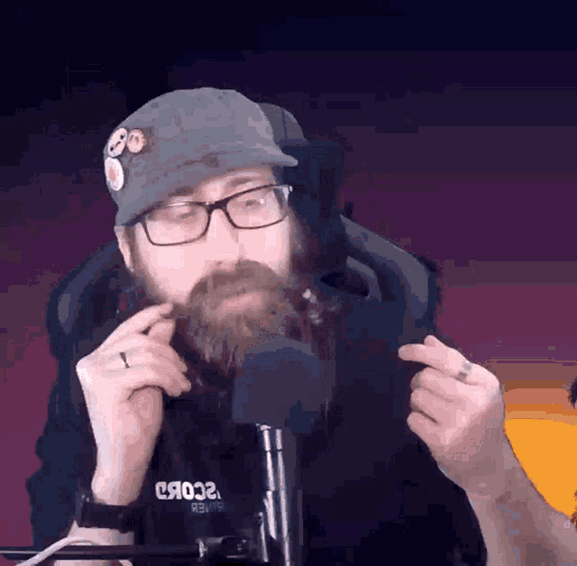 a man with a beard and glasses is sitting in front of a microphone