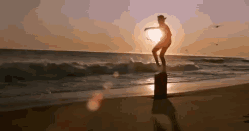 a man is standing on a wooden post on the beach .