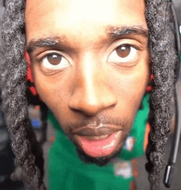 a close up of a man 's face with dreadlocks and a headset on .