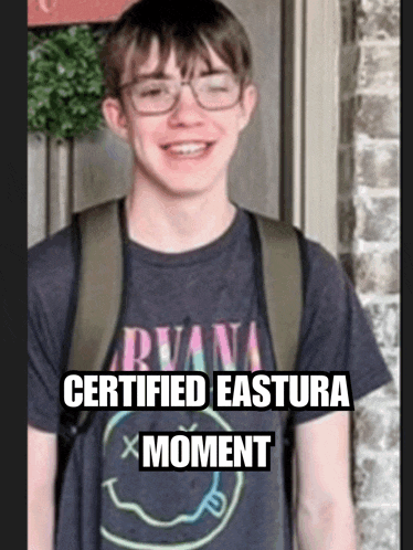 a young man wearing a certified eastura moment t-shirt is smiling