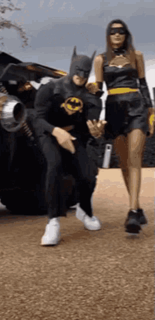 a man in a batman costume is sitting on a woman 's lap .