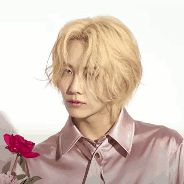 a young man with blonde hair is holding a red rose