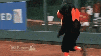 a mascot is running on a baseball field with a mlb.com logo in the background