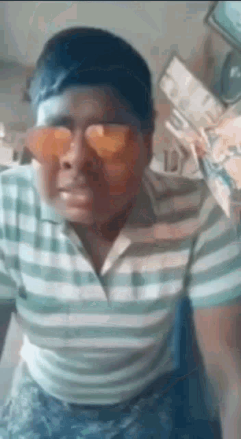 a man wearing sunglasses and a striped shirt is making a face .