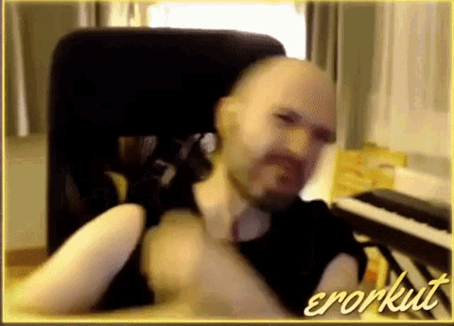 a man with a beard is sitting in front of a piano and the name errorkut is on the bottom right