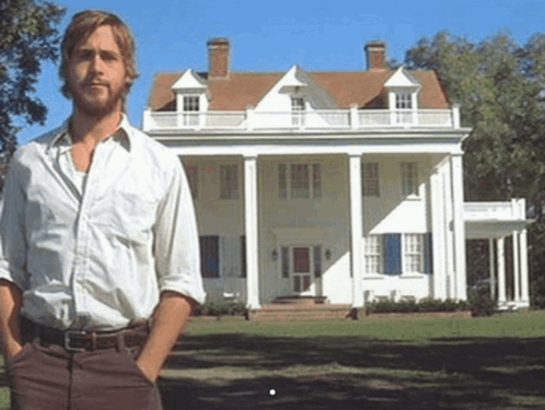 a man standing in front of a large white house
